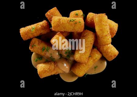 Draufsicht Stapel köstlicher, würziger gebratener Mozzarella-Sticks mit leckerer Sauce und Kräutern auf schwarzer Oberfläche gestapelt Stockfoto