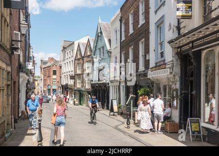 Spaziergänger und ein Mann, der entlang der Saddler Street im Stadtzentrum von Durham, England, Großbritannien, radelt Stockfoto