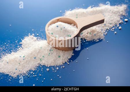 Von oben Haufen von weißen antibakteriellen Pulver für die Waschmaschine in Holzlöffel auf blauem Hintergrund in hellen Studio verstreut Stockfoto