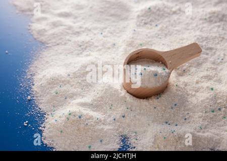 Von oben aus Holz Messbecher auf unordentlichen blauen Tisch mit Haufen verstreuten Seifenpulver in Licht Studio platziert Stockfoto