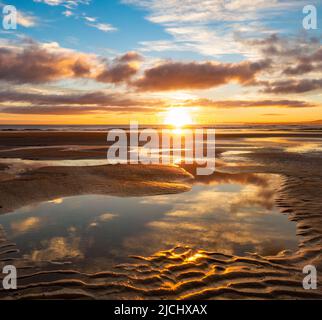 Atemberaubender Sonnenaufgang mit Spiegelungen auf dem Küstenpfad von England am Strand von Seaton Carew, Nordostengland, Großbritannien. Stockfoto