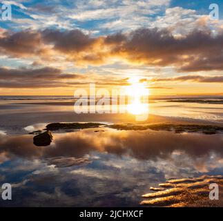 Atemberaubender Sonnenaufgang mit Spiegelungen auf dem Küstenpfad von England am Strand von Seaton Carew, Nordostengland, Großbritannien. Stockfoto