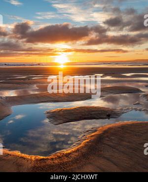 Atemberaubender Sonnenaufgang mit Spiegelungen auf dem Küstenpfad von England am Strand von Seaton Carew, Nordostengland, Großbritannien. Stockfoto