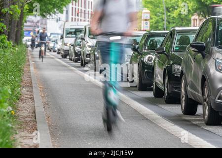 Ein E-Scooter auf dem Radweg überholt Autos im Stau Stockfoto