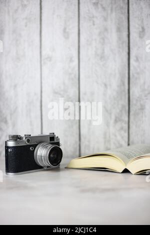 Vintage-Kamera neben einem offenen Buch auf hellem Hintergrund Stockfoto