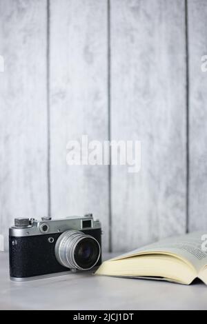 Vintage-Kamera neben einem offenen Buch auf hellem Hintergrund Stockfoto