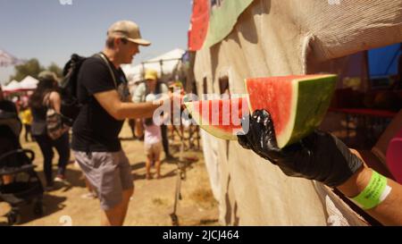 Los Angeles, USA. 12.. Juni 2022. Am 12. Juni 2022 erhalten die Menschen beim California Watermelon Festival 2022 in Los Angeles, Kalifornien, USA, kostenlose Wassermelonenscheiben. Das California Watermelon Festival 2022 fand am Wochenende in Los Angeles statt, mit kostenlosen Wassermelonen, Live-Musikshows, Karnevalsfahrten und anderen lustigen Aktivitäten für Familien. Quelle: Zeng Hui/Xinhua/Alamy Live News Stockfoto