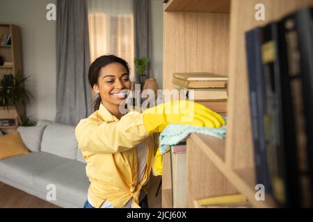 African Lady Staubbeutel Bücherregal Mit Rag Tragen Handschuhe Reinigung Im Innen Stockfoto