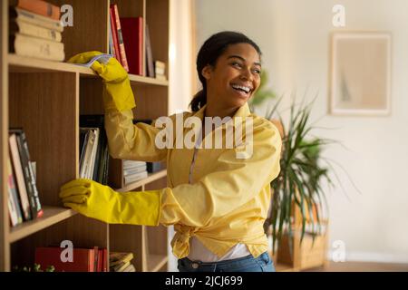 Glücklich Schwarze Frau Staubbände Regale Reinigung Möbel Zu Hause Stockfoto