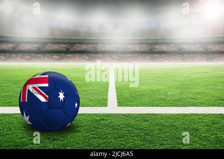 Fußball in Australien in einem hell erleuchteten Stadion im Freien mit einer bemalten australischen Flagge. Konzentrieren Sie sich auf den Vordergrund und den Fußball mit geringer Schärfentiefe auf BA Stockfoto