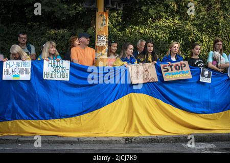 Sofia, Bulgarien, 13. Juni 2022: Die Menschen, die eine riesige ukrainische Flagge und Streikschilder zur Unterstützung der Ukraine halten, stehen in einer Reihe gegenüber dem russischen emb Stockfoto