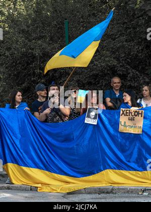 Sofia, Bulgarien, 13. Juni 2022: Die Menschen mit ukrainischen Flaggen und Streikschildern zur Unterstützung der Ukraine stehen in einer Reihe gegenüber der russischen Botschaft in Stockfoto