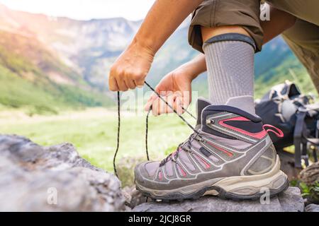 Frau, die im Sommer im Freien Wanderstiefel auf Wanderwegen bindet. Stockfoto