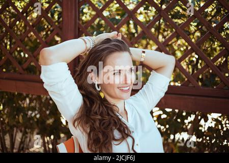 Entspannte, moderne Frau im weißen Hemd auf der Terrasse. Stockfoto