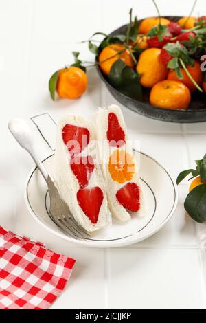 Japanisches Fruits Sandwich Furutsu Sando mit Erdbeere und Orange auf weißem Holzhintergrund, chaotisch Styling Stockfoto