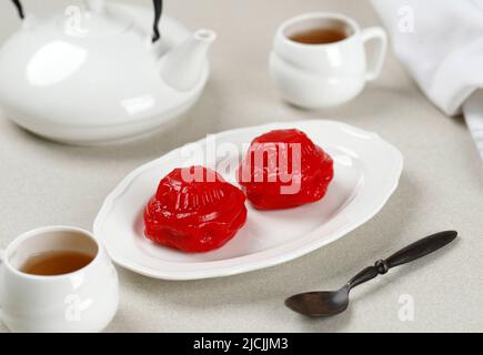 Angku Kueh oder Kue Ku, Red Tortoise Cake mit Mungbean Paste Füllung, beliebt als Kue Thok. Serviert mit Tee Stockfoto