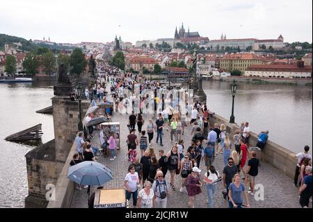 Prag, Tschechische Republik. 05.. Juni 2022. Passanten laufen über die Karlsbrücke vor der Prager Burg. Quelle: Sebastian Kahnert/dpa/Alamy Live News Stockfoto