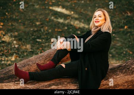 Schöne Momente der Herbstspaziergänge in der Natur mit schönem Blond in Wollmantel, Strickpullover und Jeans. Schöne Frauen. Herbstporträt Stockfoto