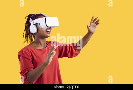 Glückliche afroamerikanische Frau in innovativem VR-Headset, die virtuelle Realität erlebt Stockfoto