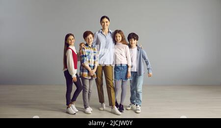 Gruppenportrait von glücklichen Kindern zusammen mit ihrer Lehrerin im Studio Stockfoto