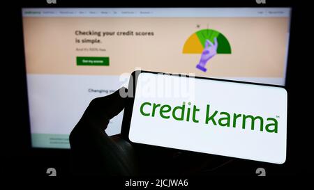 Person, die Mobiltelefon mit dem Logo des US-Finanzunternehmens Credit Karma Inc. Auf dem Bildschirm vor der Geschäftswebseite hält. Konzentrieren Sie sich auf die Telefonanzeige. Stockfoto