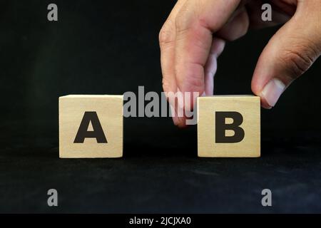 Plan B oder Backup- und Verfügbarkeitsplan im Geschäftskonzept. Hand wählt B gegen A in Holzblöcken auf dunkelschwarzem Hintergrund. Stockfoto