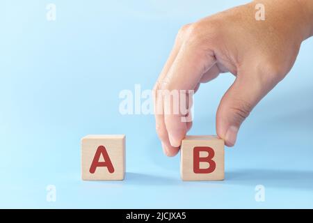 Plan B oder Backup- und Verfügbarkeitsplan im Geschäftskonzept. Hand wählt B gegen A in Holzblöcken auf blauem Hintergrund. Stockfoto