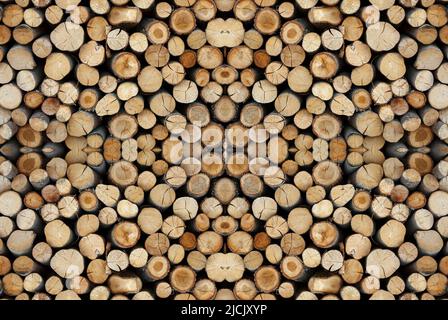 Hintergrund eines zerrissenen alten Holzstamms mit Altersringen, die im Freien auf einem Stapel getrocknet werden. Brennholzstapel, nahtloses horizontales und vertikales Muster Stockfoto