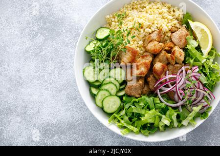 Salatschüssel mit Schweinebab-Bulgur, Gurke, Salat, Thymian und Senfsauce Stockfoto