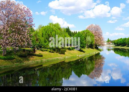 Weiße schöne Wolken am blauen Himmel mit Spiegelung am Fluss Stockfoto