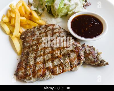 Gegrilltes Schweinesteak mit Pommes auf dem Teller Stockfoto