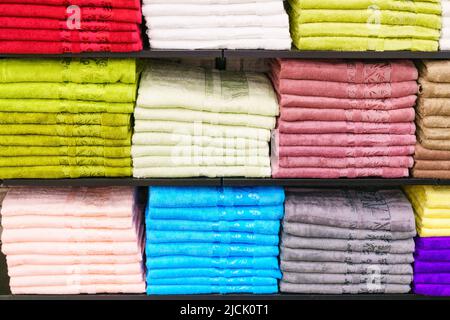 Mehrfarbige Handtücher im Regal auf dem Markt, Verkauf Baumwollhandtücher, Stapel farbige Baumwollhandtücher, ein Regal in der heimischen Reihe des Marktes, Nahaufnahme selektiven Fokus Stockfoto
