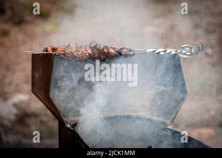 Lammfleisch auf Spießen wird auf dem Grill im Freien gebraten Stockfoto