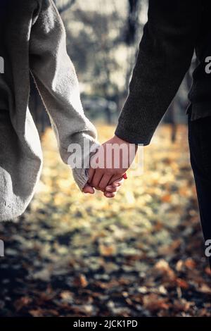 Nahaufnahme eines verliebten Paares, das beim Gehen die Hände hält. Selektiver Fokus, vertikal Stockfoto