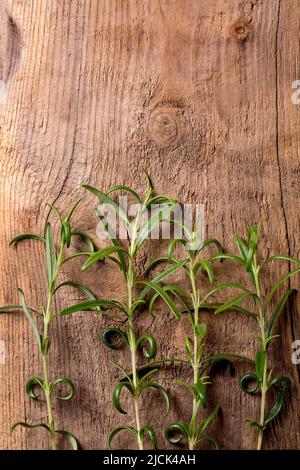 Frische Bio-Gartenrosemarste in Reihe auf altem Holzhintergrund. Draufsicht, Kopierbereich Stockfoto