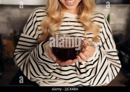 Junge unkenntliche Frau lächelt weit und hält eine Tasse Kaffee Stockfoto