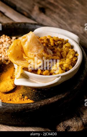 Dhal mit Roti-Brot. Traditionelles indisches Gericht aus gelber Erbse mit Roti-Fladenbrot, serviert mit Zitrone in einer Keramikschale auf einem alten Holztisch. Stockfoto