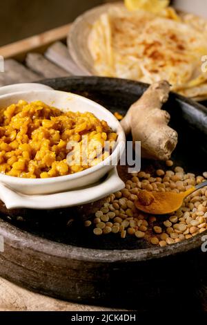 Dhal mit Roti-Brot. Traditionelles indisches, gelbes Erbsen-Food-Limonengrün mit Roti-Fladenbrot, serviert mit Zitrone in einer Keramikschale auf einem alten Holztisch. Stockfoto