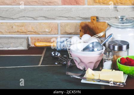 Vorbereitung für das Backen. Eier, Butter, Zucker, Mehl und Himbeeren auf Küchentisch, Kopierplatz. Stockfoto