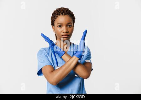 Junge schwarze Arzt trägt Uniform machen Stop-Geste isoliert auf weißem Hintergrund Stockfoto