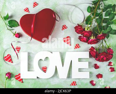 Festliche Komposition der Liebe zum Valentinstag mit roter Geschenkbox und Rosen, Herzen und Wort Liebe. Flach liegend. Stockfoto