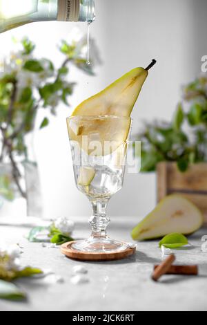 Birne Sirop ist in einem Glas mit Birne Cocktail mit frischem Obst und Blumen auf hellgrauem Hintergrund dekoriert gießen. Sommer kalt Birne trinken Limonade w Stockfoto