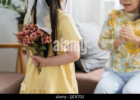 Ein glücklicher Moment der kleinen Tochter überrascht ihre liebende Mutter im Urlaub mit Blumen Stockfoto