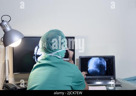 Im medizinischen Labor wird der Patient unter Aufsicht eines Radiologen einer MRT- oder CT-Untersuchung unterziehen, im Kontrollraum beobachtet der Arzt Stockfoto