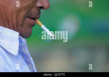 Bhaktapur, Bagmati, Nepal. 14.. Juni 2022. Ein Mann raucht eine Zigarette, als er am Dienstag eine Pause vom Pflanzen neuer Sämlinge von Reiskulturen in Bhaktapur macht. (Bild: © Amit Machamasi/ZUMA Press Wire) Stockfoto