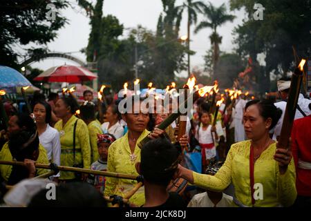 Ältere Frau mit traditioneller Fackel für eine Reihe von Veranstaltungen zum Nyepi-Tag in Kediri, Eastjava, Indonesien Stockfoto
