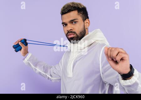 Bärtiger afroamerikanischer Mann, der Springseil isoliert auf Purpur hält Stockfoto