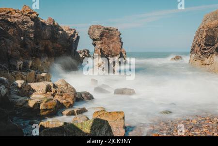 Eine kleine Bucht am Girdle Ness Lighthouse außerhalb des Hafens von Aberdeen in Schottland, in der das Wasser durch lange Exposition verlangsamt wird. Stockfoto