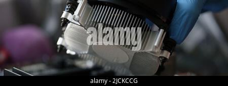 Person, die einen schwarzen Kühlerlüfter mit Kupferrohren am Computerprozessor installiert Stockfoto