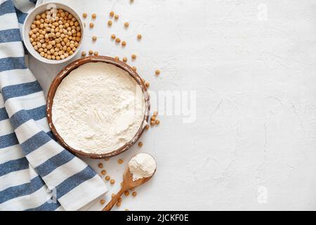Kichererbsen und Mehl in Keramikschale auf weißem Hintergrund Stockfoto
